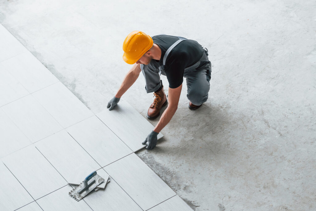 a tiles contractor is installing the tiles in construction side with safety helmet